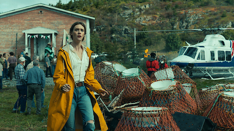 A Below character in a yellow raincoat beside lobster traps and a coastal building in Newfoundland