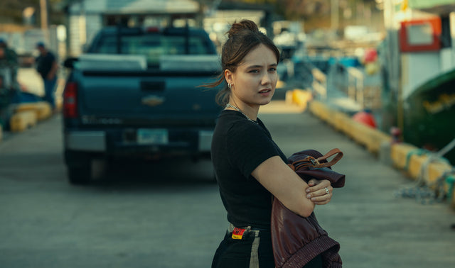 A young woman stands on a working dock in Newfoundland in Netflix's Below