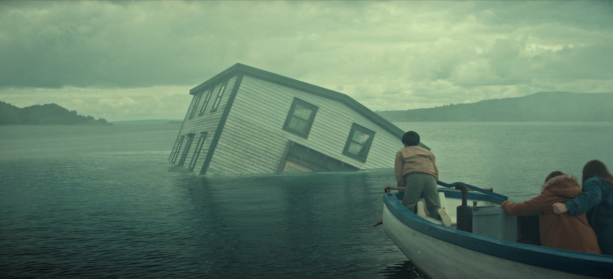 A family watches a house sink into the water in Netflix's Below, illustrating the show's opening mystery