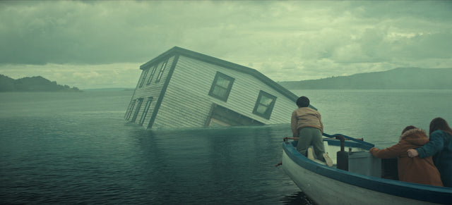 A family watches a house sink into the water in Netflix's Below, illustrating the show's opening mystery
