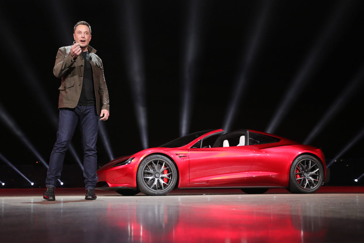 Elon Musk standing beside the Tesla Roadster at its original unveiling