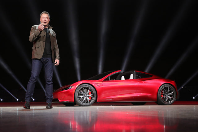 Elon Musk standing beside the Tesla Roadster at its original unveiling