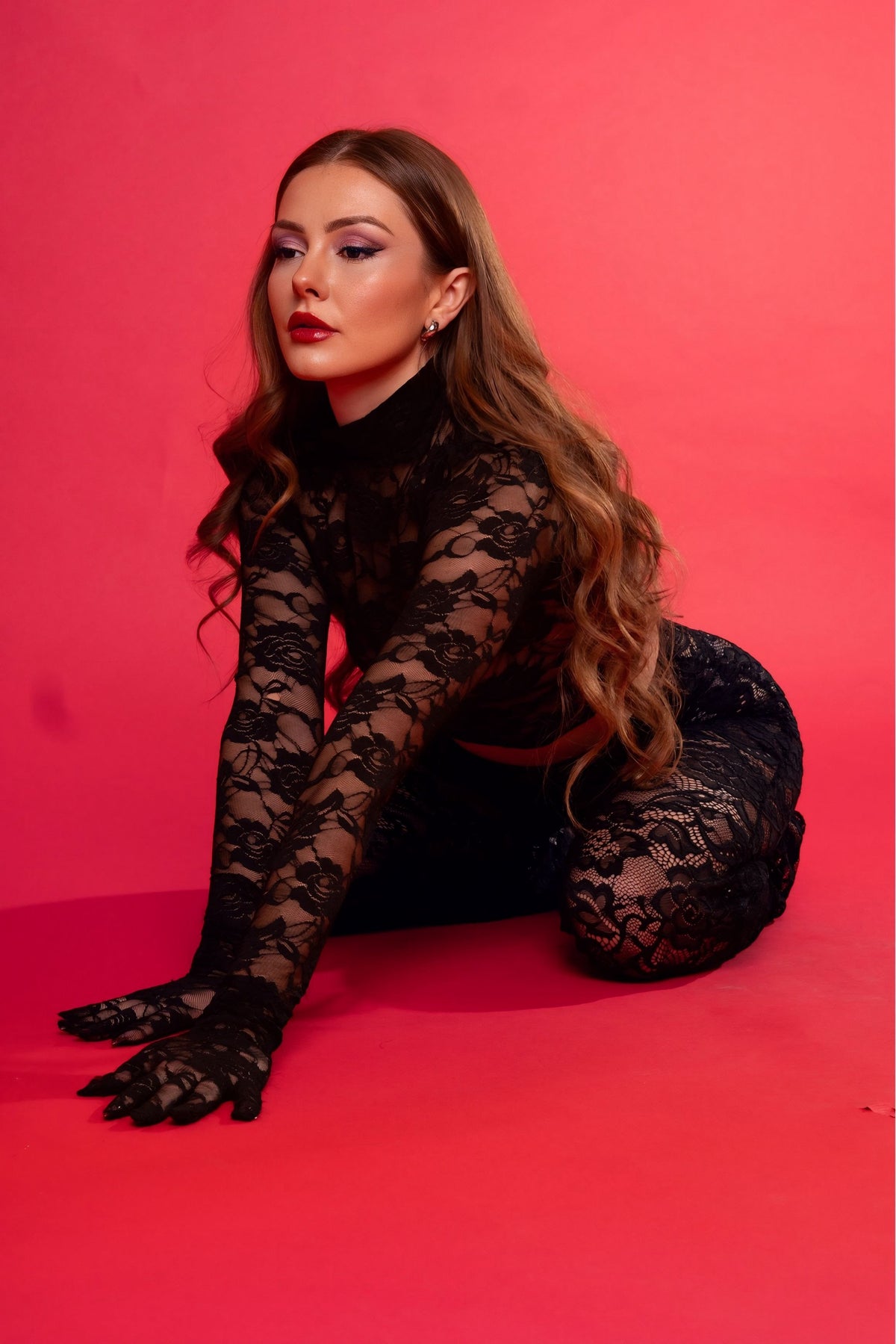 Kara Leona in a black lace outfit in a studio portrait from her official website