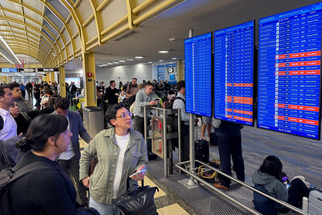 Travelers check flight information boards at a US airport