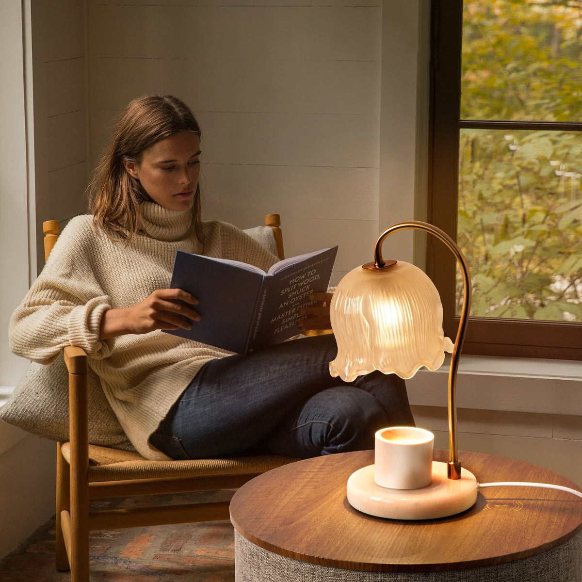 Woman reading beside a glowing vintage-style candle warmer lamp on a side table