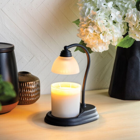 Candle Warmers Etc. black Aurora candle warmer lamp warming a white jar candle on a tabletop