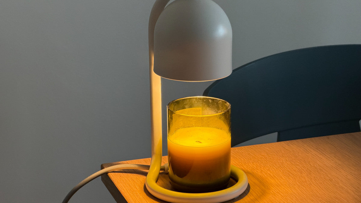White candle warmer lamp heating a jar candle on a wooden tabletop. Illustrative reference for this article; exact model match not independently verified.